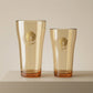 Sienna Glow amber borosilicate glass tumbler with gold Cupid decal available in 12oz and 17oz sizes.SOLA & SIENNA